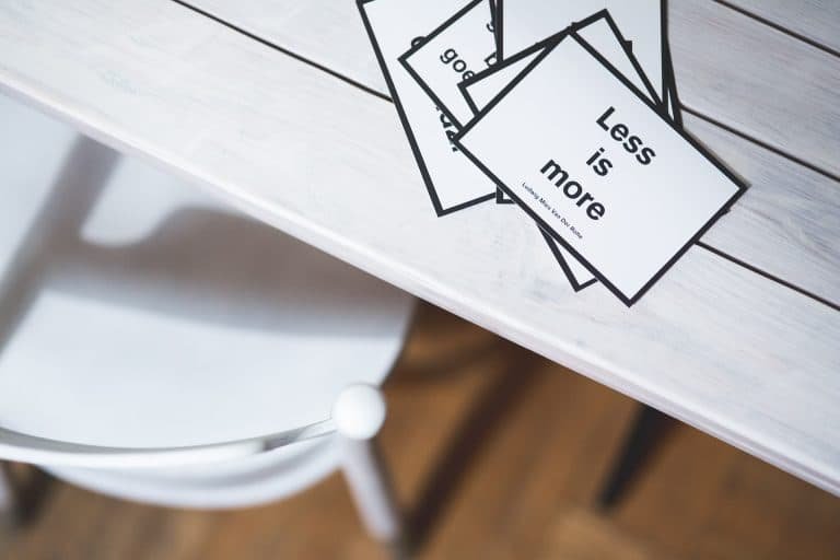 Kaartjes met less is more op een witte tafel