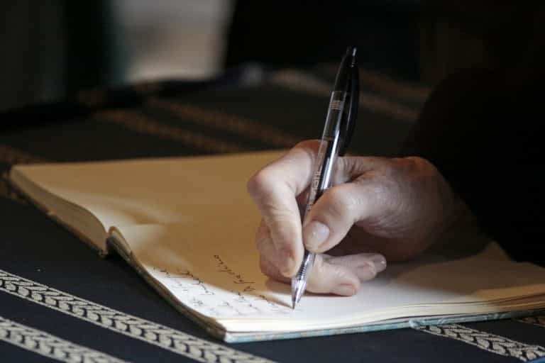 Hand schrijft met een pen in een notitieboek