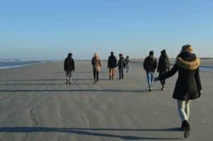 Wandelaars op een breed strand van een Waddeneiland in de zon