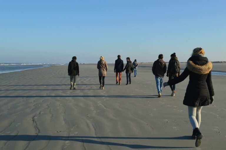 Wandelaars op een breed strand van een Waddeneiland in de zon