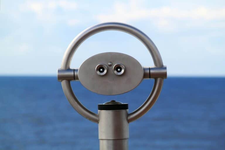 Verrekijker op een paal met uitzicht over een blauwe zee