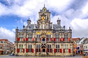 Stadhuis van Delft op de Markt onder een blauwe lucht met wolken