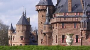 Kasteel met spitse torens en rode bakstenen muren achter een grasveld