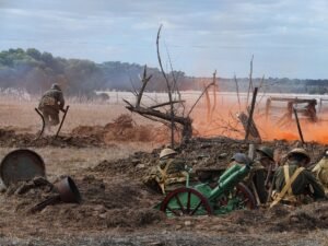 Nagespeeld slagveld met rook, kale bomen en een oud kanon