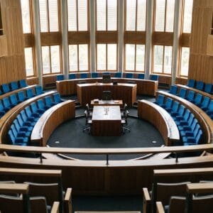 Lege halfronde vergaderzaal met rijen blauwe stoelen links en rechts van de plek van de voorzitter