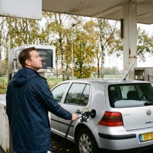 Man tankt een zilveren Volkswagen Golf en kijkt naar de oplopende teller van de benzinepomp