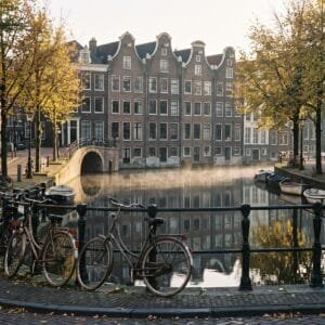 Stenen brug met fietsen over een Amsterdamse gracht met grachtenpanden in het ochtendlicht