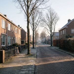 Straat met een rij rijtjeshuizen en een vrijstaand huis in de lage zon van een winterochtend