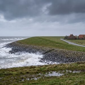 Hoge golven slaan op een grijze winterochtend tegen een Zeeuwse zeedijk met daarachter een polder met boerderijen