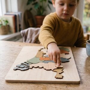 Kind legt een stukje in een houten puzzel van de kaart van Nederland met gekleurde provincies