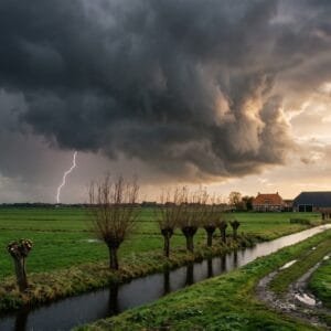 Donkere onweerswolk met een bliksemflits boven een vlak polderlandschap met een sloot en knotwilgen